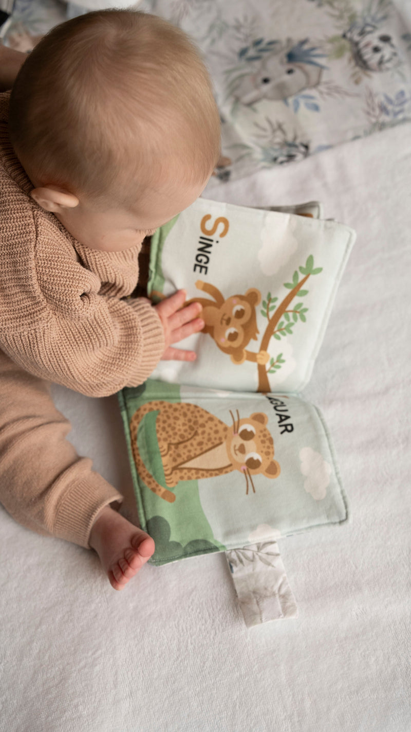 petit garçon de 6 mois qui regarde un livre d'éveil la nature des petits